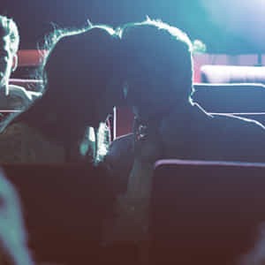 映画館の暗闇の中でキスするカップル