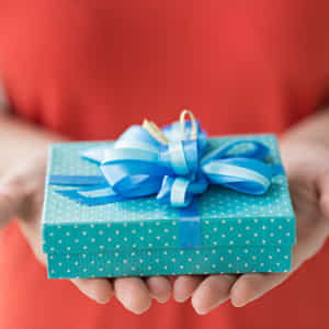 赤いドレス女性が水色の水玉柄の箱にブルーのリボンをつけたプレゼントを差し出している
