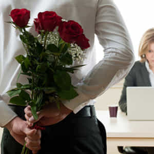 職場内でバラの花束を持って女性にアプローチをしようとしている男性